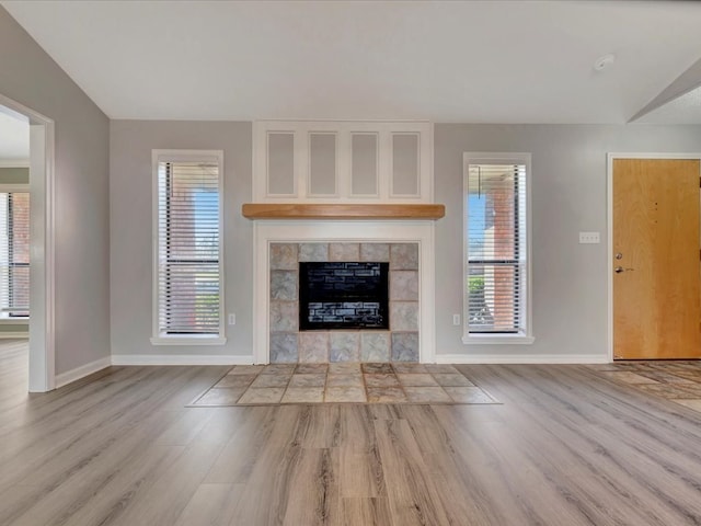 unfurnished living room with light wood-style floors, a fireplace, and baseboards