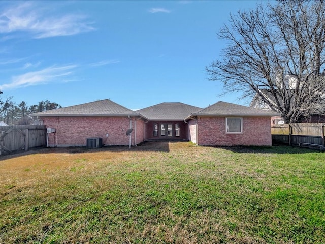 back of house featuring brick siding, a fenced backyard, and a yard