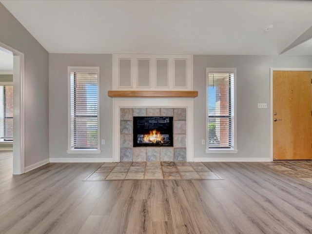 unfurnished living room featuring light wood finished floors, a fireplace, and baseboards