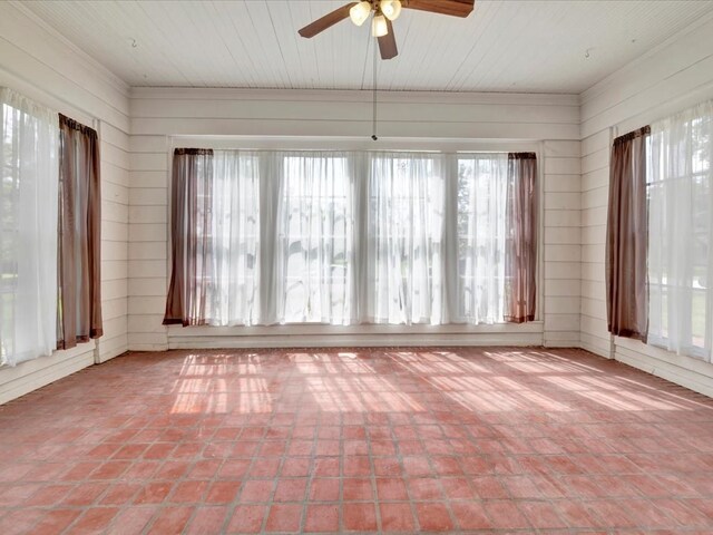 unfurnished sunroom featuring ceiling fan and a healthy amount of sunlight