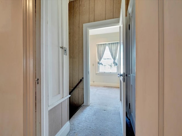 corridor featuring wooden walls and light colored carpet