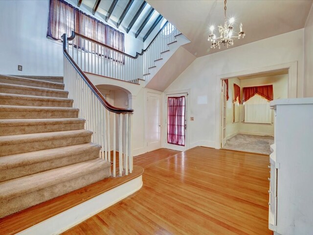 foyer entrance with wood-type flooring, a high ceiling, and a chandelier