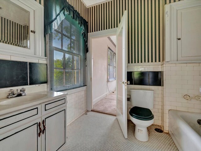 bathroom with tile patterned floors, vanity, tile walls, and toilet