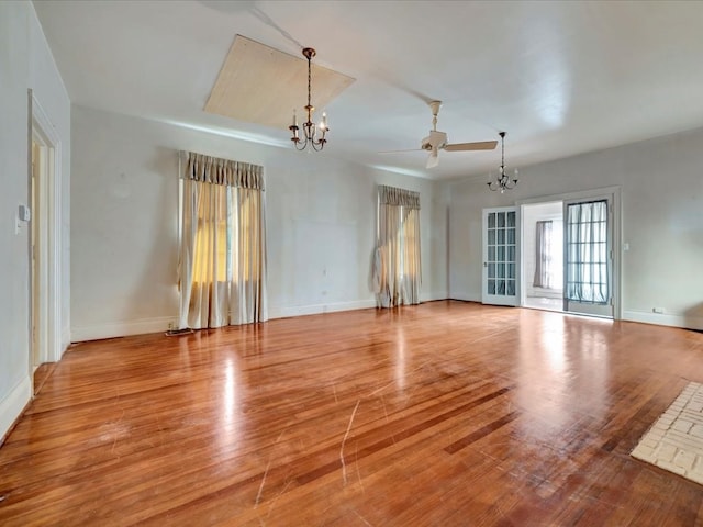 spare room with ceiling fan with notable chandelier and light hardwood / wood-style floors