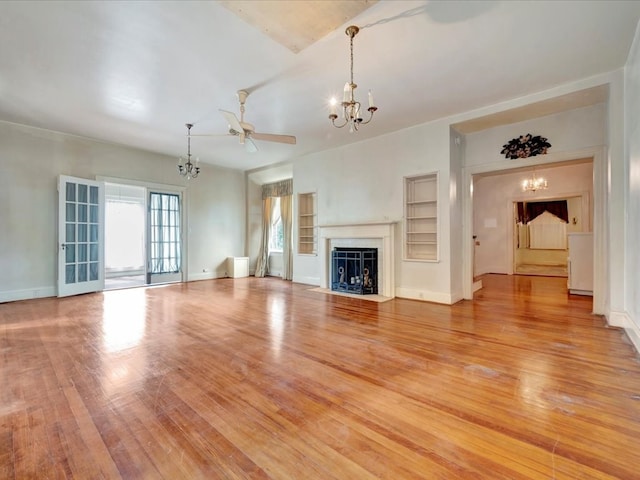 unfurnished living room with ceiling fan with notable chandelier and light hardwood / wood-style flooring