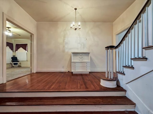 staircase featuring hardwood / wood-style flooring and ceiling fan with notable chandelier