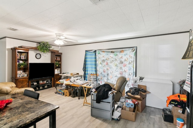 living area with light wood finished floors, ceiling fan, visible vents, and ornamental molding