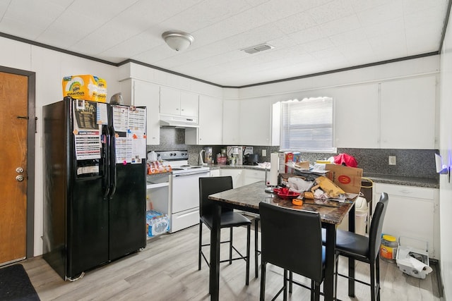 kitchen featuring white electric stove, black fridge, dark countertops, and white cabinetry