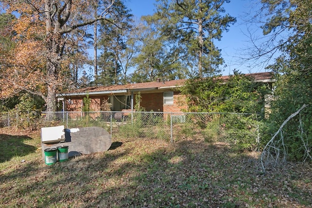 rear view of house featuring brick siding, a lawn, and fence