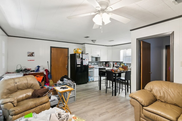 living area featuring a ceiling fan, visible vents, ornamental molding, and light wood finished floors