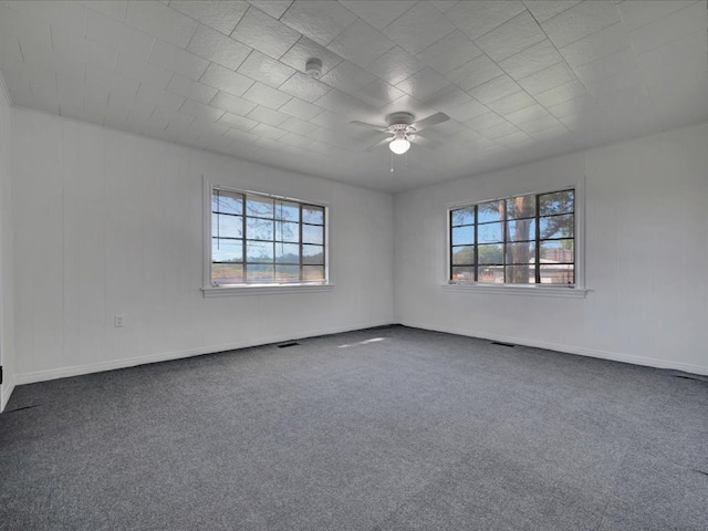 carpeted spare room featuring a wealth of natural light and ceiling fan