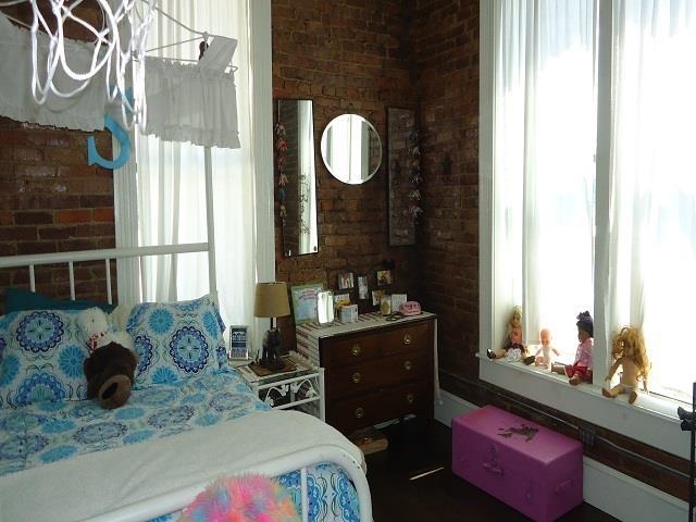 bedroom featuring multiple windows and brick wall