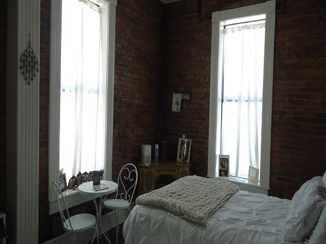 bedroom featuring brick wall and multiple windows