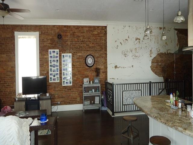 living room with dark hardwood / wood-style floors, ceiling fan, crown molding, and brick wall