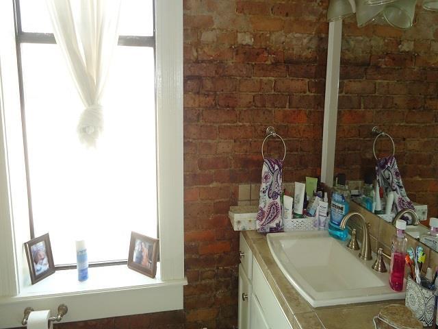 bathroom with vanity and brick wall