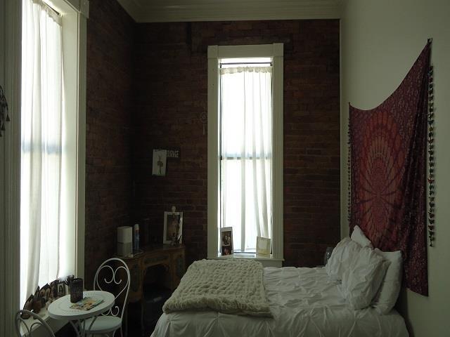 bedroom featuring crown molding and brick wall