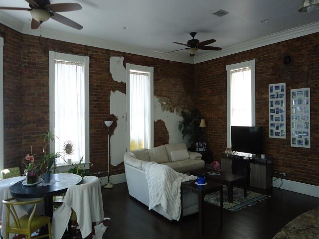 152 N Oak St, Hemphill, TX 75948 - living room with ceiling fan, dark wood-type flooring, brick wall, and ornamental molding
