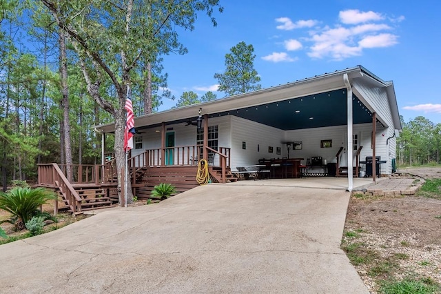 view of front of property with a porch, stairway, concrete driveway, a ceiling fan, and a carport