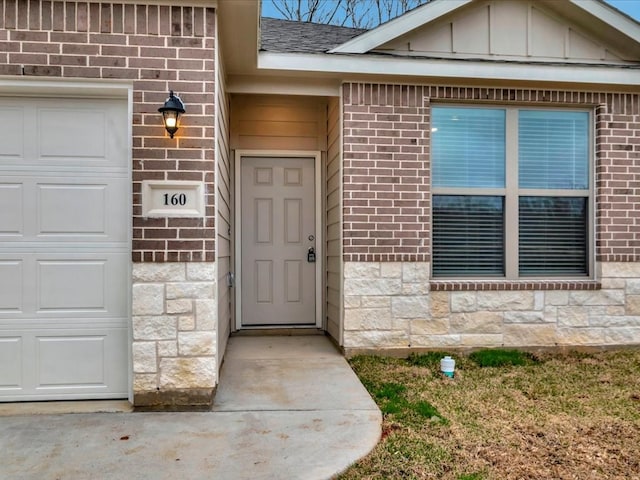 property entrance featuring a garage, stone siding, brick siding, and board and batten siding