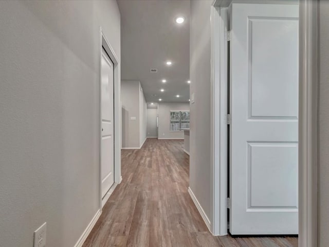 corridor featuring recessed lighting, visible vents, baseboards, and wood finished floors