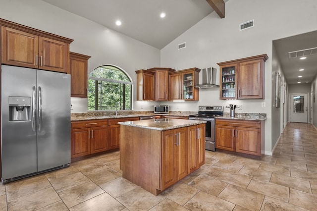 kitchen featuring wall chimney range hood, beamed ceiling, high vaulted ceiling, a kitchen island, and appliances with stainless steel finishes