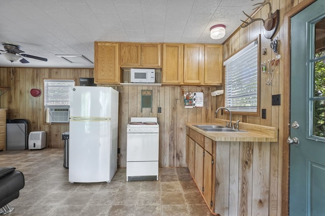 kitchen featuring white appliances, ceiling fan, wooden walls, and sink