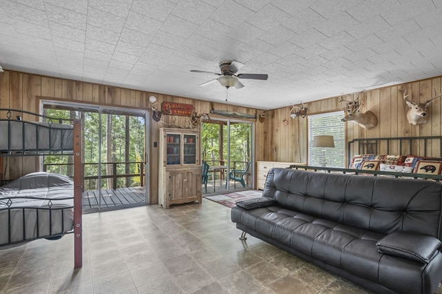 living room with a wealth of natural light, ceiling fan, and wood walls