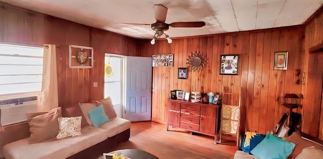 living area featuring cooling unit, ceiling fan, light hardwood / wood-style flooring, and wood walls