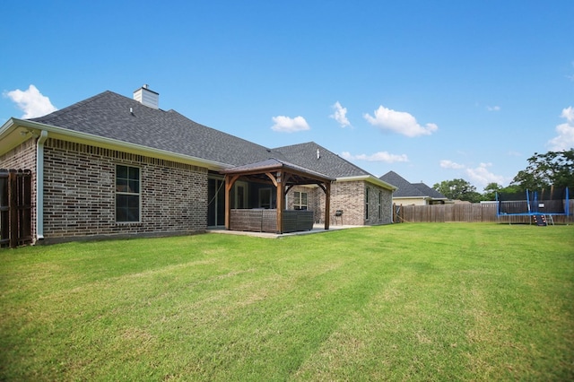 169 Shady Oaks Loop, Lufkin, TX 75904 - rear view of property with a trampoline, brick siding, a fenced backyard, and a chimney