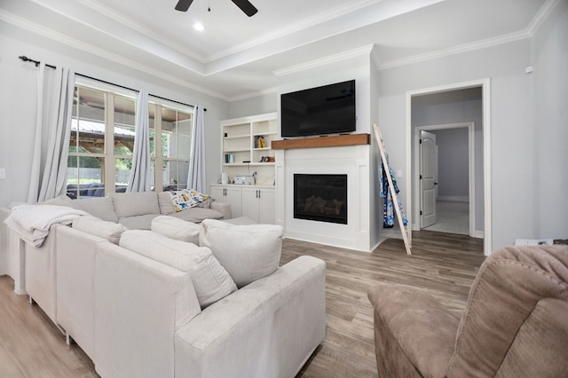 169 Shady Oaks Loop, Lufkin, TX 75904 - living area with ceiling fan, light wood finished floors, a glass covered fireplace, crown molding, and a raised ceiling