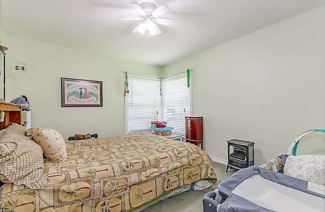 carpeted bedroom featuring ceiling fan and a wood stove