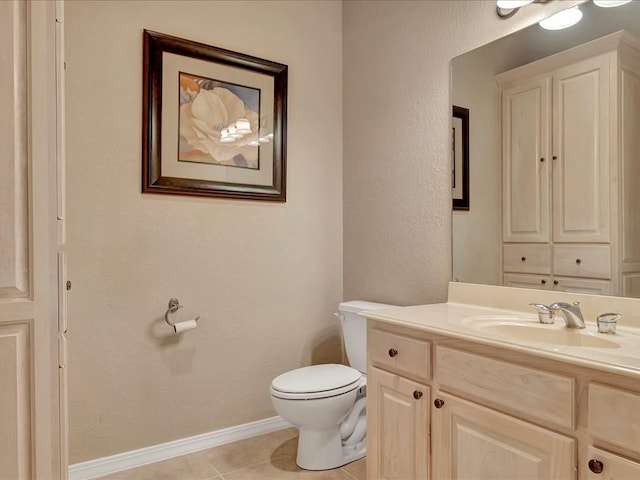 bathroom featuring tile patterned floors, a textured wall, toilet, vanity, and baseboards