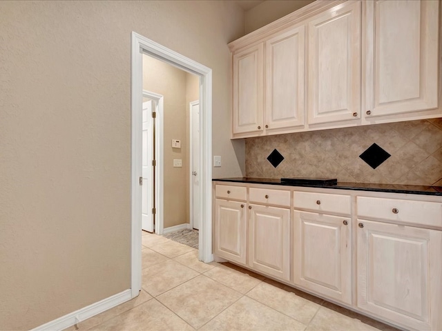 kitchen featuring backsplash, baseboards, dark countertops, and light tile patterned flooring