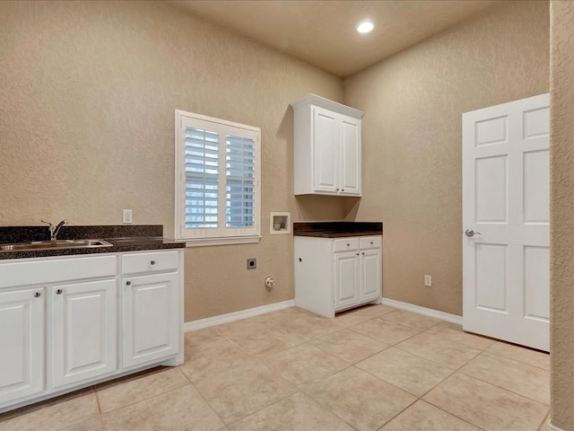 clothes washing area featuring a sink, electric dryer hookup, light tile patterned floors, cabinet space, and washer hookup