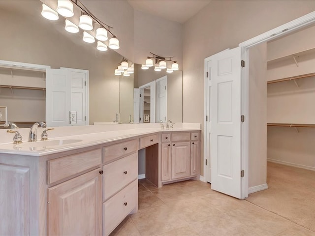 bathroom featuring a walk in closet, tile patterned floors, a sink, and double vanity