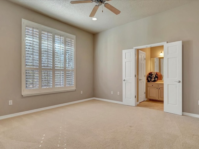 unfurnished bedroom featuring a textured ceiling, baseboards, recessed lighting, light colored carpet, and ensuite bath