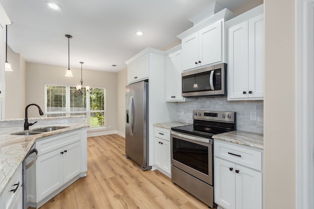 211 Rustic Pines Dr, Lufkin, TX 75904 - kitchen featuring appliances with stainless steel finishes, white cabinets, backsplash, light wood-style floors, and decorative light fixtures