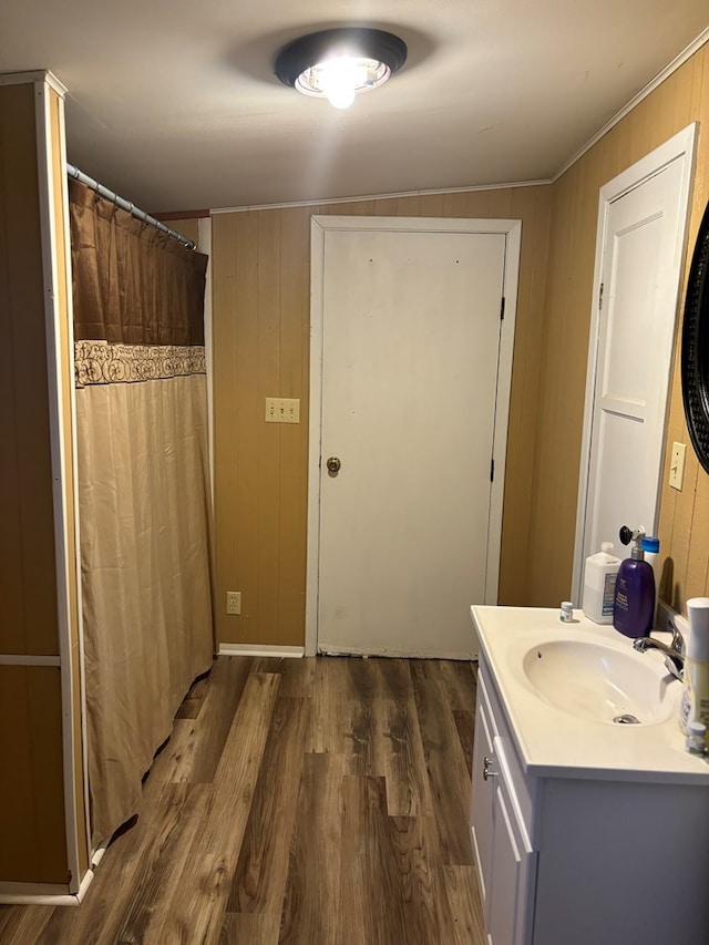 bathroom with wood walls, curtained shower, wood finished floors, and vanity