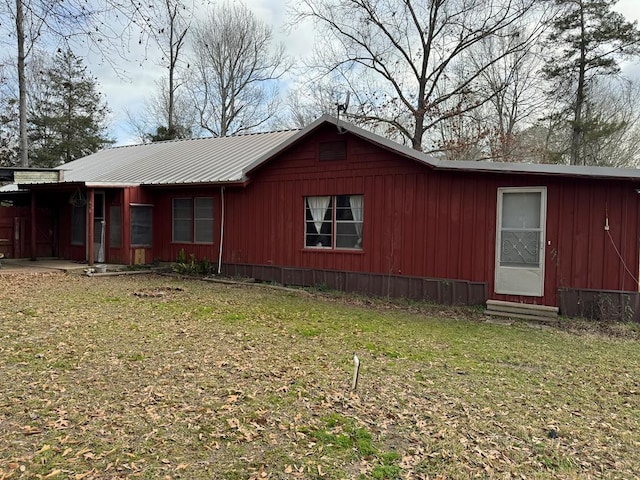 view of front of house featuring entry steps, metal roof, and a front yard