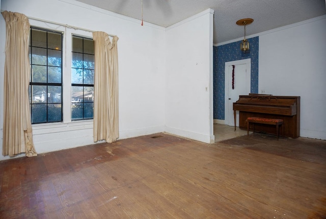 empty room with baseboards, wood-type flooring, ornamental molding, and a textured ceiling