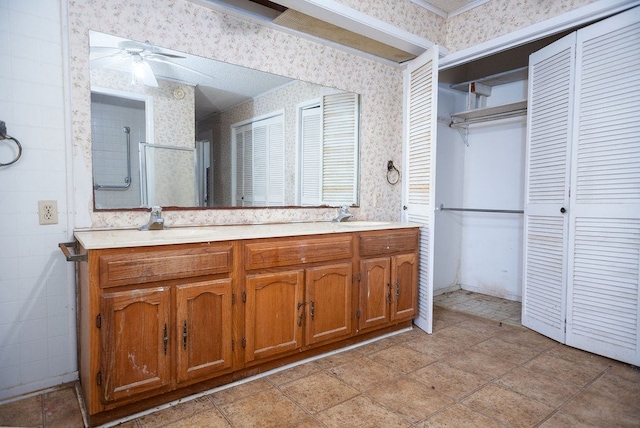 bathroom featuring a ceiling fan, a closet, double vanity, and wallpapered walls