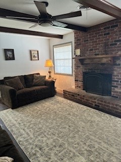 living room with beamed ceiling, a brick fireplace, and ceiling fan
