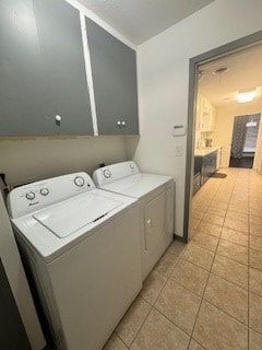 clothes washing area featuring separate washer and dryer, light tile patterned flooring, and cabinet space