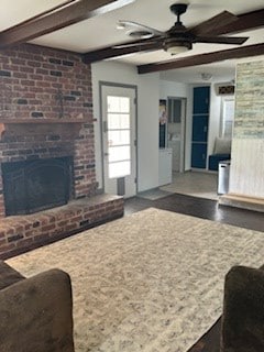 living area featuring ceiling fan, a brick fireplace, and beam ceiling