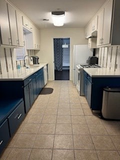 kitchen featuring blue cabinetry, stainless steel gas range, a sink, and light countertops