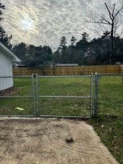 view of gate featuring fence and a lawn