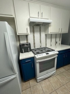 kitchen with white gas stove, freestanding refrigerator, blue cabinets, and under cabinet range hood