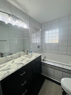 bathroom featuring toilet, tile walls, vanity, and bathing tub / shower combination