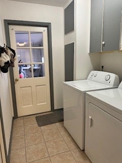 clothes washing area featuring cabinet space, washing machine and clothes dryer, and light tile patterned floors