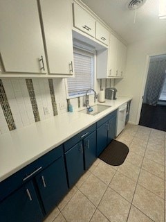 kitchen featuring white cabinets, light tile patterned floors, a sink, and blue cabinetry
